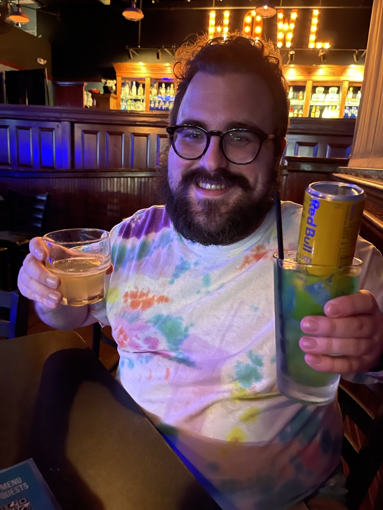 Kurt holding two drinks in a bar